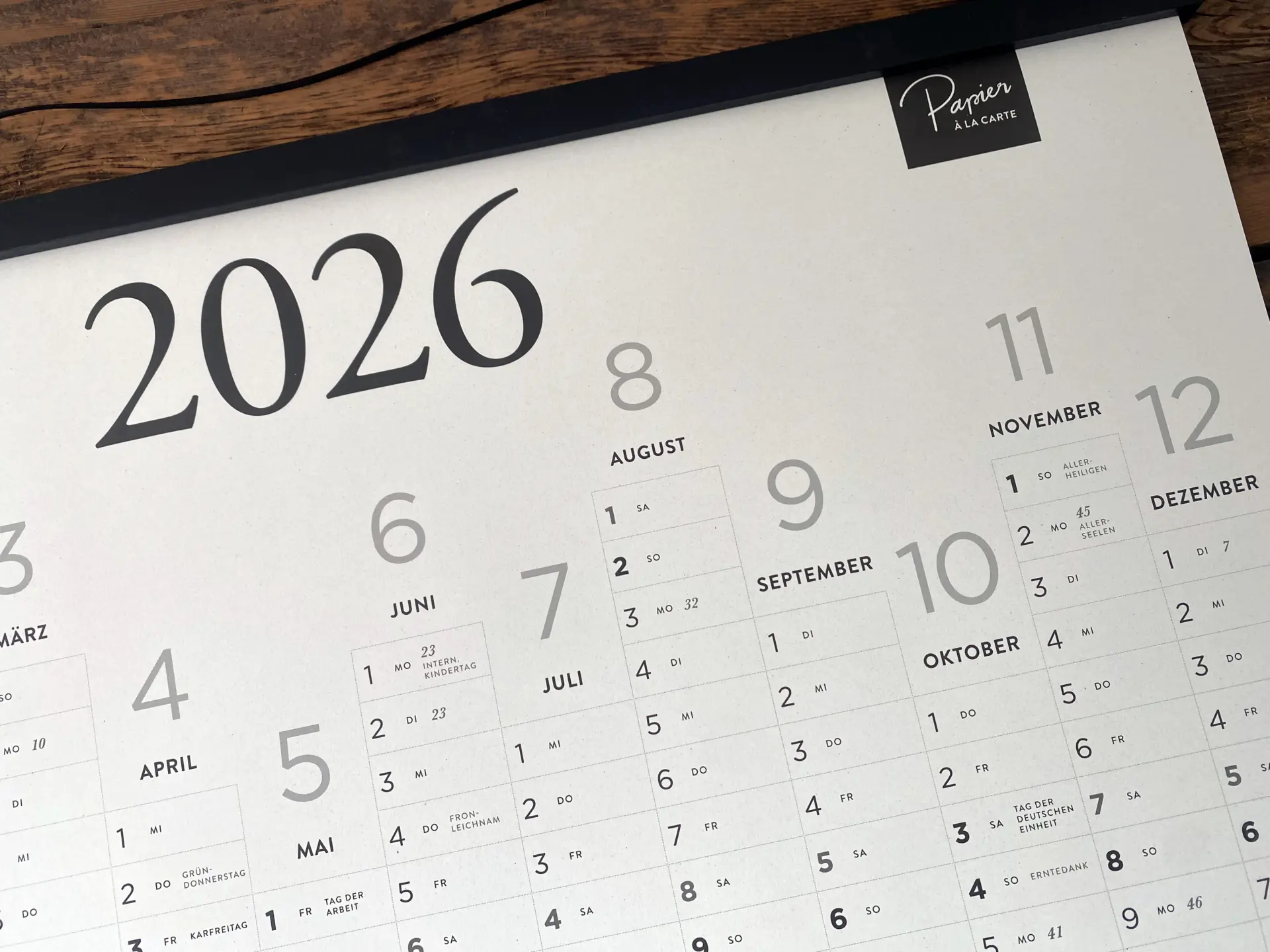 Detailaufnahme des Jahreskalenders 2026 aus Apfelpapier in DIN A1 mit Monatsübersicht und schwarzer Magnet-Posterleiste.