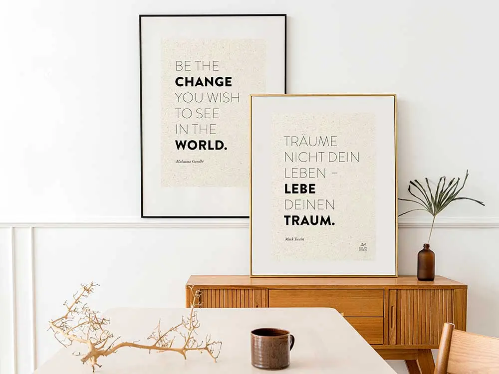 Zwei gerahmte Poster mit inspirierenden Zitaten im skandinavischen Stil auf Graspapier an weißer Wand