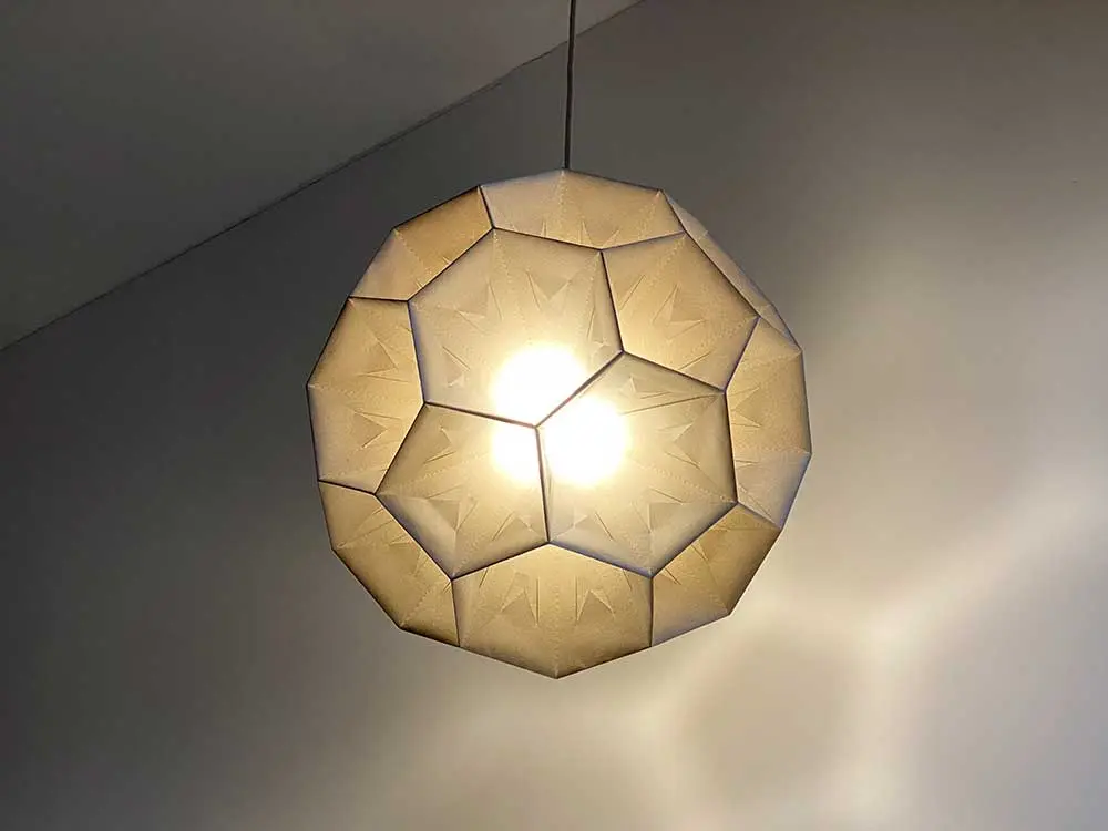 Papierlampe leuchtet an weißer Decke mit weichem Lichtschein