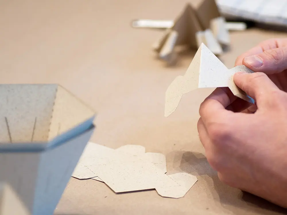 Hände beim Falten eines Origami-Papierteils für eine Leuchte im Workshop bei Papier à la Carte
