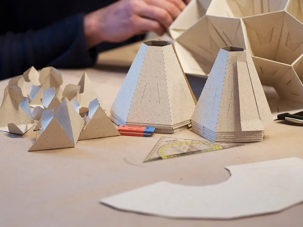 Händisch gefaltete Module für eine nachhaltige Origami-Deckenlampe aus Naturpapier