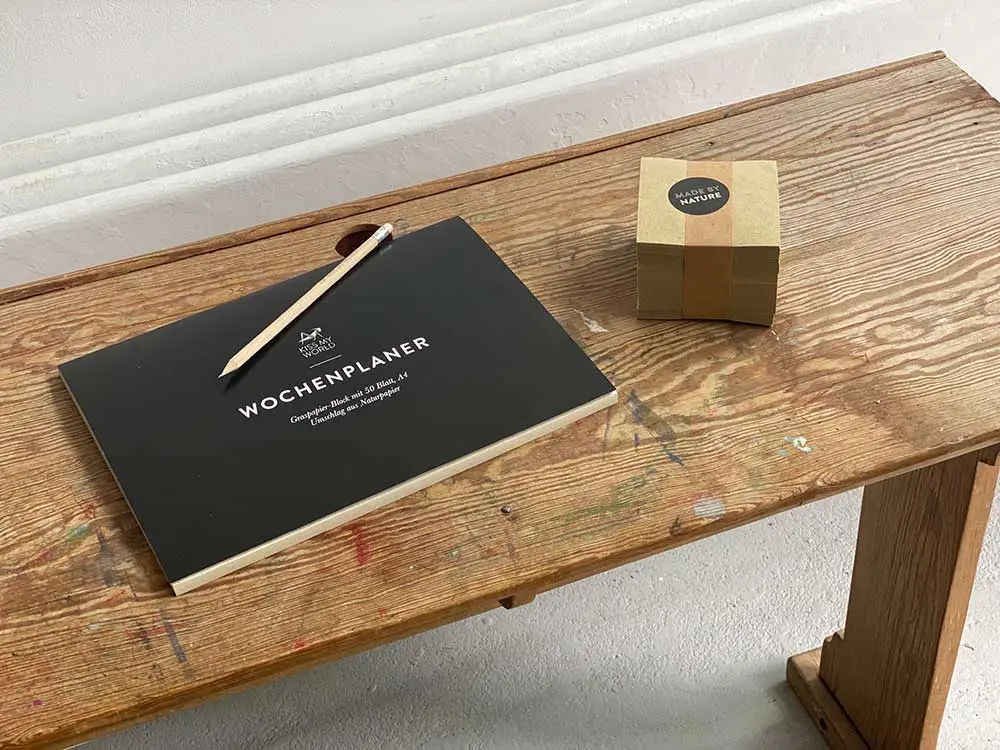 Wochenplaner aus Graspapier und Naturpapier auf alter Holz-Schulbank mit Bleistift