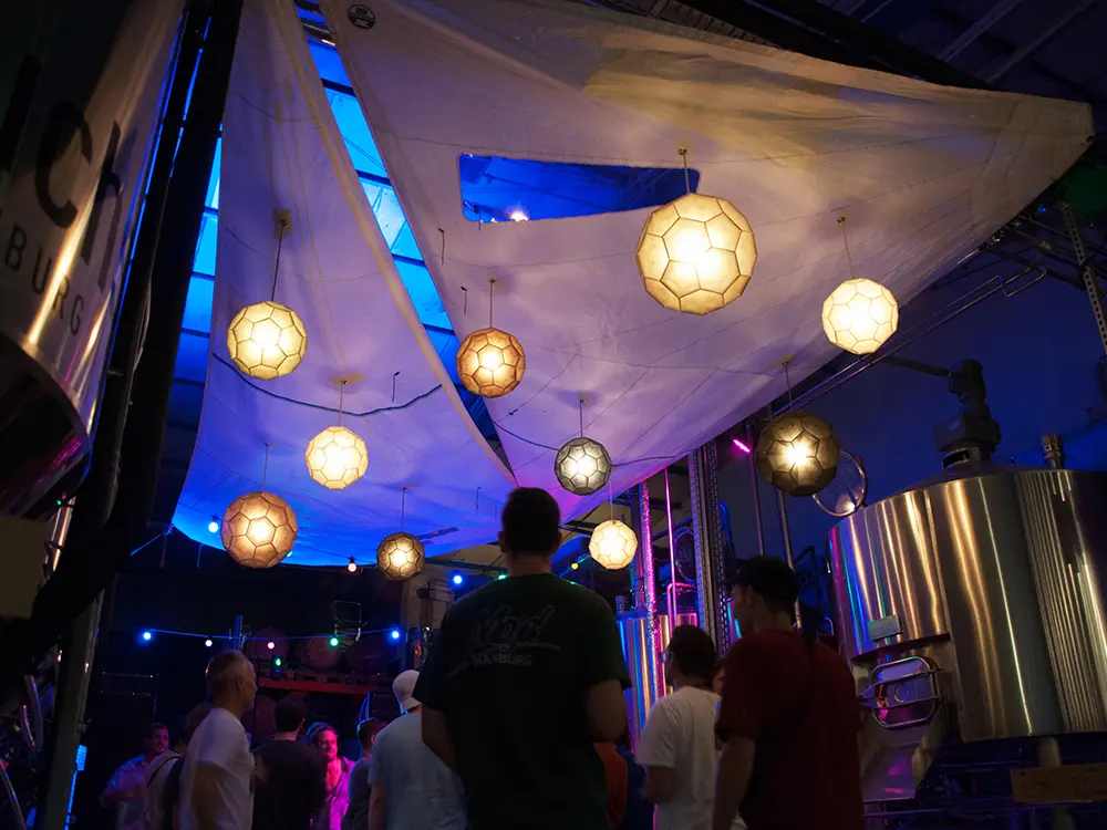 Nachhaltige Papierleuchten auf einem Event, stimmungsvoll beleuchtet unter einem weißen Segel.