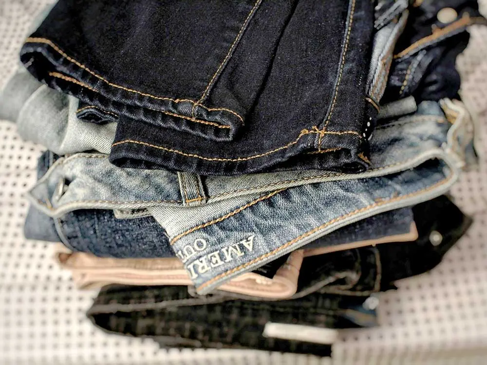 Papier à la Carte_Jeanspapier_Jagotech_06 Nahaufnahme eines Stapels Jeans-Stoffe und Jeanshosen / Denim für das Recycling. Daraus kann später Jeanspapier hergestellt werden und die Leute können z.B. unsere Papier à la Carte-Notizbücher aus Jeanspapier kaufen