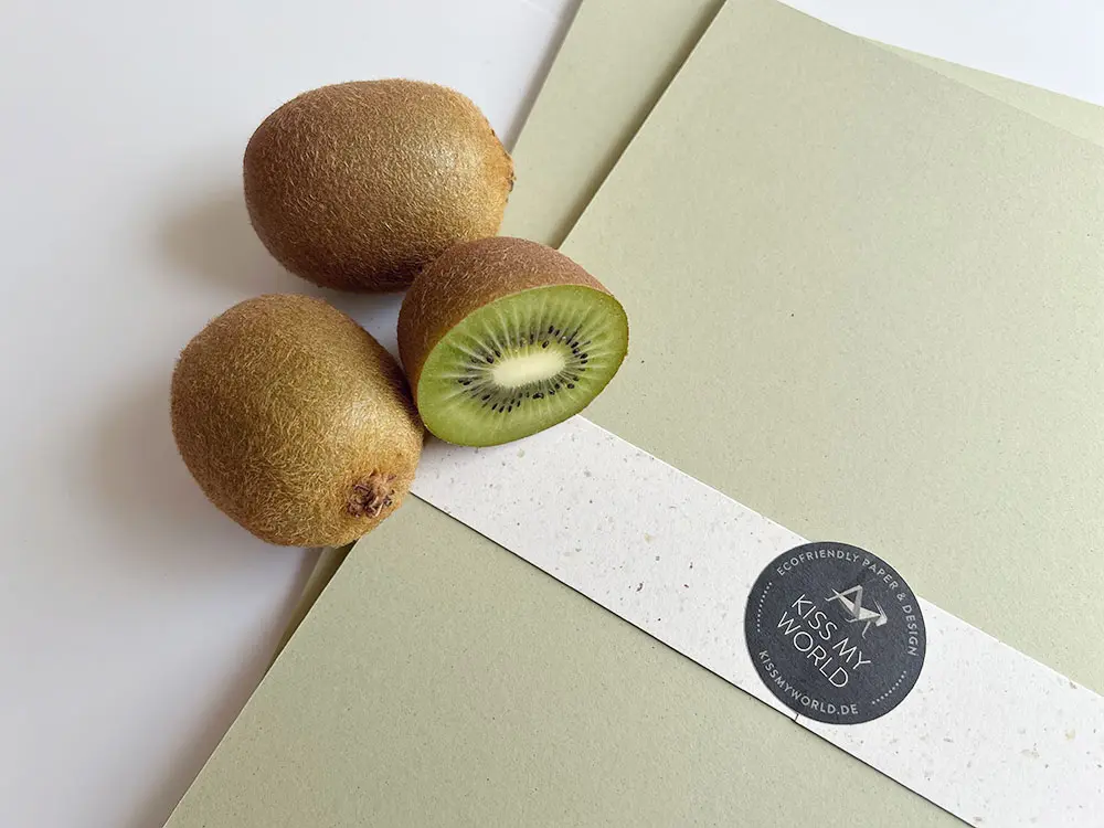 Drei Kiwis liegen auf einem grünen Tonpapier aus Kiwipapier.