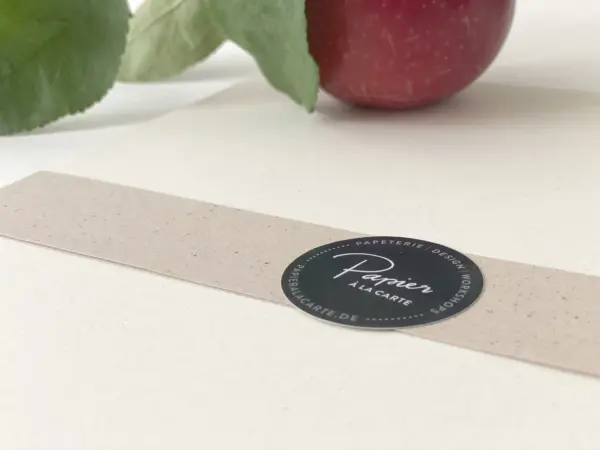 Nahaufnahme eines Apfelpapier-Tonpapier mit Banderole und Apfel im Hintergrund
