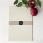 Apfelpapier-Bogen im A4-Format im Set mit Banderole und frischen Äpfeln – naturweißes Papier aus Apfeltrester